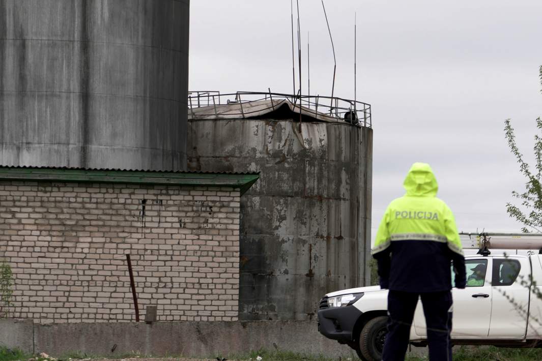 Полицейский осматривает повреждения нефтяного резервуара после крушения дронов в Резекне, Латвия