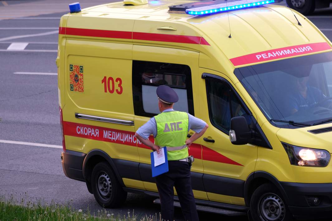 Сотрудник Дорожно-патрульной службы ГИБДД и автомобиль скорой медицинской помощи на дороге