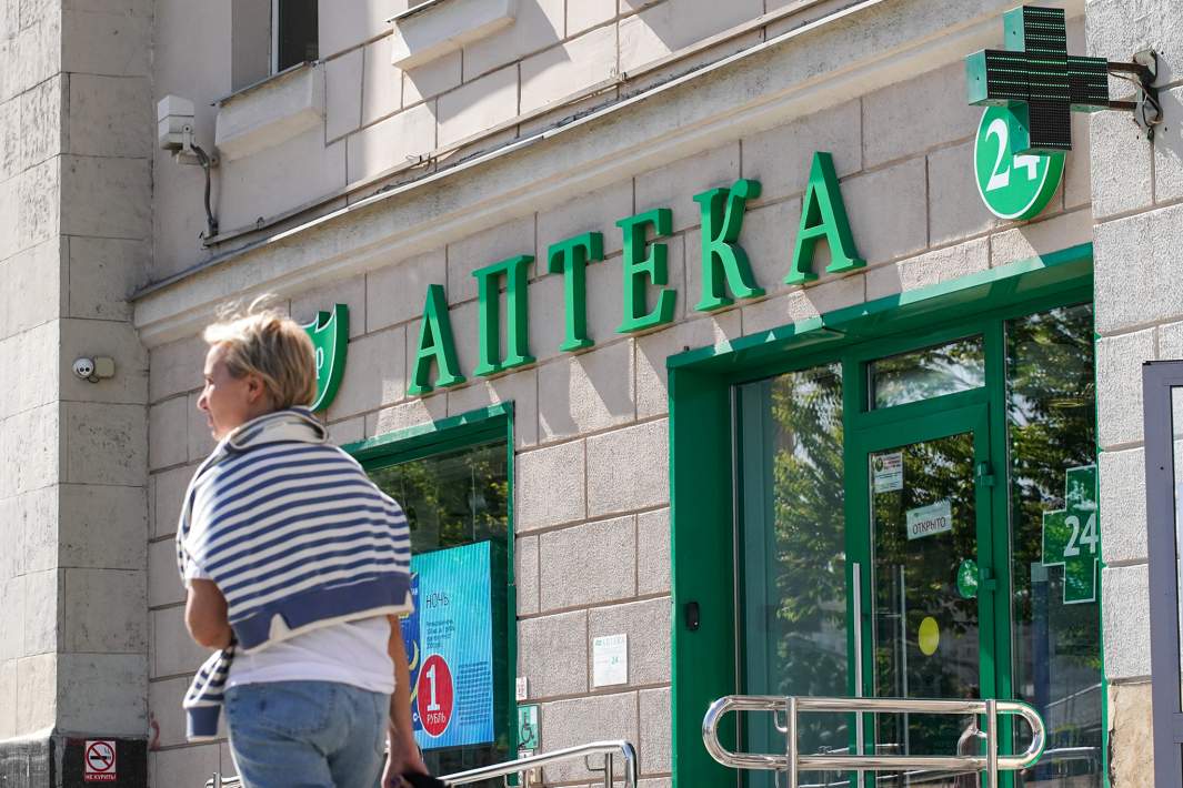 Люди идут по улице мимо аптеки