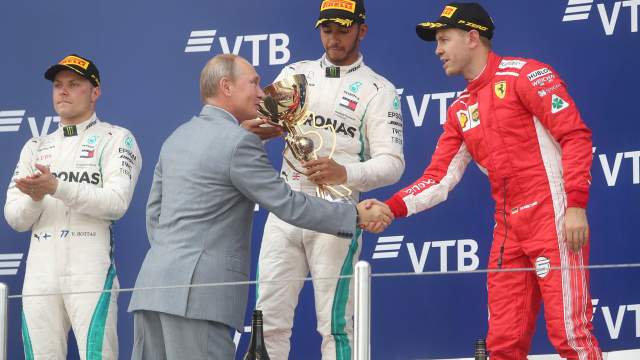 Президент РФ Владимир Путин на церемонии награждения призеров российского этапа чемпионата мира по кольцевым автогонкам в классе "Формула-1" на "Сочи Автодроме". Слева - гонщик команды «Мерседес» Валттери Боттас, в центре - гонщик команды «Мерседес» Льюис Хэмилтон, справа - гонщик команды «Феррари» Себастьян Феттель  