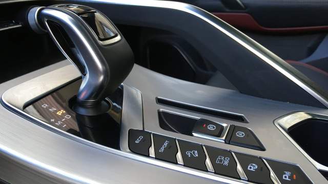 Центральный тоннель, как и большинство других деталей в интерьере, выполнены из матового алюминия. А расположение селектора семиступенчатого робота и кнопок управления режимами работы силовых агрегатов и прочих ассистентов чем-то напомнили салон Porsche