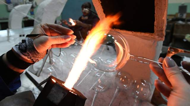 Стеклодув создаёт стеклянный новогодний шар на фабрике игрушек "Бирюсинка" в Красноярске. 