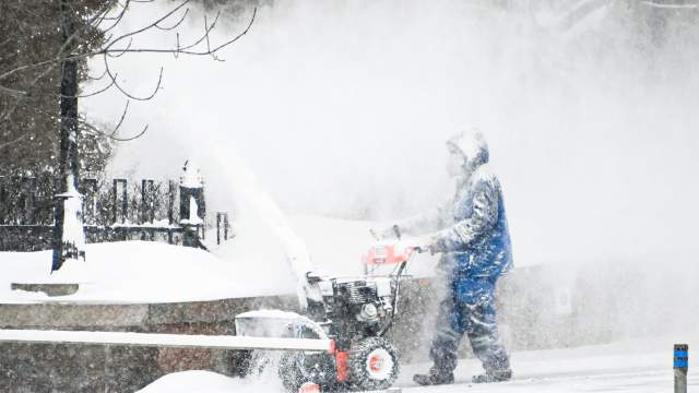 Сотрудник коммунальных служб убирает снег на улице в центре Москвы