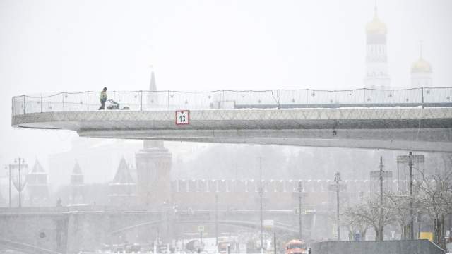 Сотрудник коммунальных служб убирает снег на Парящем мосту в природно-ландшафтном парке "Зарядье" в Москве