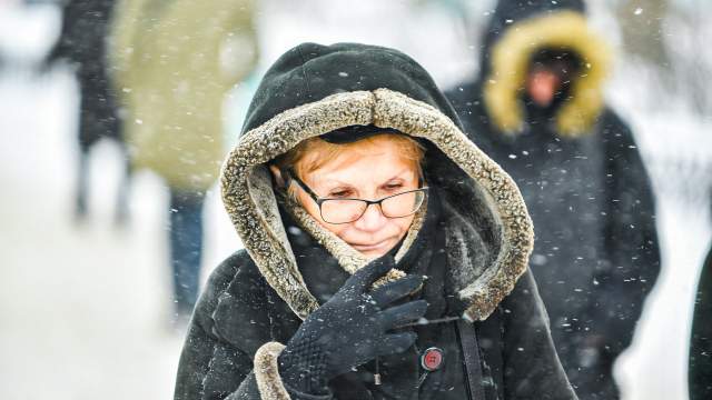 Женщина прикрывается от снега