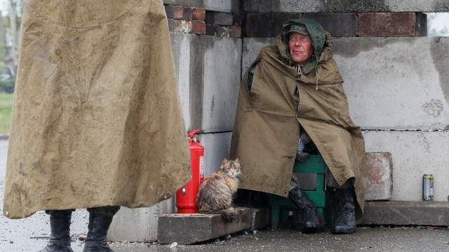 A service member of pro-Russian troops sits next to a cat before the expected departure of Ukrainian soldiers, who surrendered at the besieged Azovstal steel mill, in the course of Ukraine-Russia conflict in Mariupol