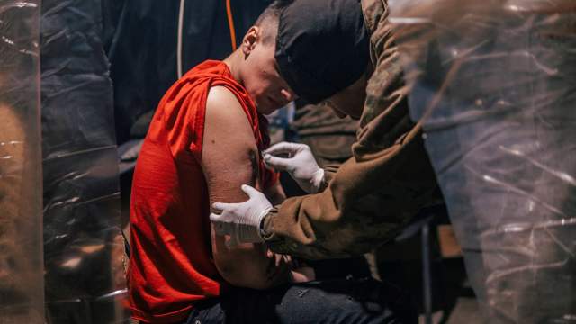 An injured Ukrainian service member receives medical assistance in a field hospital inside a bunker of the Azovstal Iron and Steel Works in Mariupol