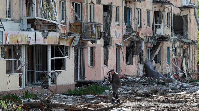 A local resident walks near a building heavily damaged during Ukraine-Russia conflict in the southern port city of Mariupol