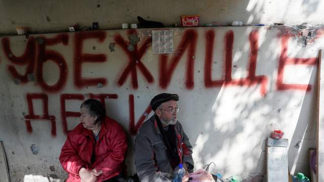 Local residents sit outside a block of flats heavily damaged during Ukraine-Russia conflict in the southern port city of Mariupol