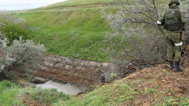 Военнослужащий ВС РФ наблюдает за движением воды после поднятия шлюза Северо-Крымского канала в Херсонской области
