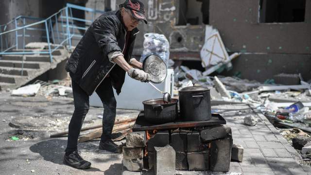 Женщина готовит еду на одной из улиц в Мариуполе