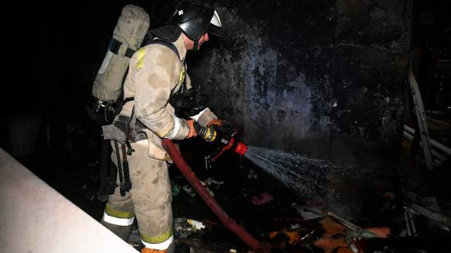 Сотрудники МЧС во время тушения пожара в доме, пострадавшем от обстрела ВСУ в Донецке