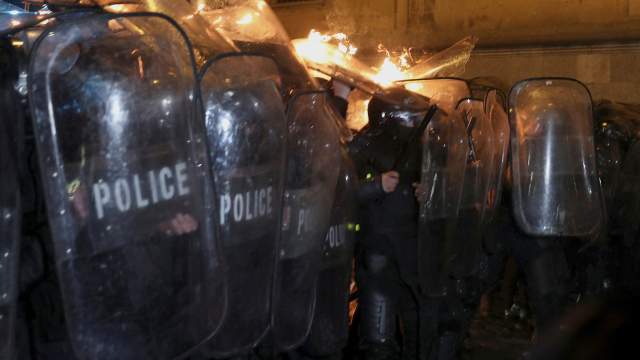 Police officers attempt to extinguish a fire, as protesters throw a Molotov cocktail during a rally against the "foreign agents" law in Tbilisi, Georgia, March 7