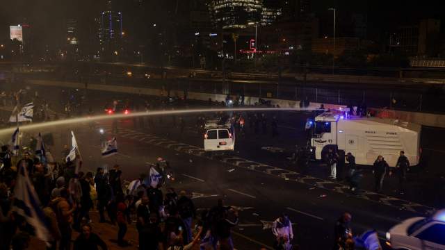 Members of the security forces use a water cannon to disperse the people attending a demonstration after Israeli Prime Minister Benjamin Netanyahu dismissed the defense minister and his nationalist coalition government presses on with its judicial overhaul, in Tel Aviv
