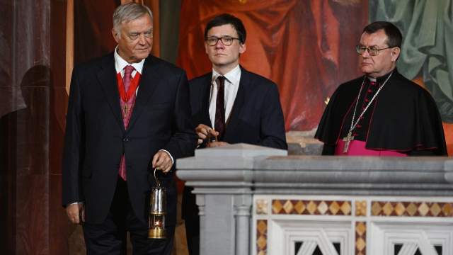 Председатель попечительского совета Фонда Андрея Первозванного Владимир Якунин вносит лампаду с частицей Благодатного огня в храм Христа Спасителя во время пасхального богослужения. Справа: председатель Конференции католических епископов России, митрополит архиепархии Божией Матери в Москве архиепископ Паоло (Павел) Пецци