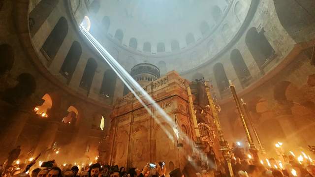 Верующие со свечами и лампадами, зажженными от Благодатного огня, в кафедральном соборе Воскресения Христова (храм Гроба Господня) в Иерусалиме