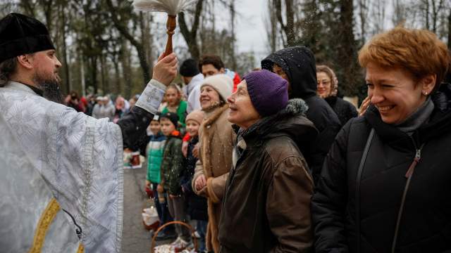 An Orthodox priest sprays holy water on believers after a service which marks the Orthodox Easter
