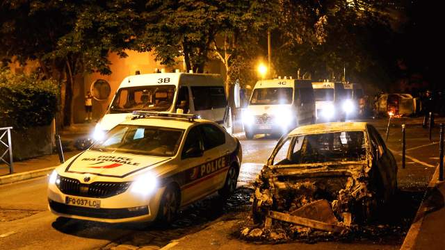 Haziran ayında Fransa'nın Paris banliyösü Nanterre'de bir trafik durması sırasında bir Fransız polis memuru tarafından öldürülen 17 yaşındaki Nahel adlı gencin ölümünün ardından, protestocularla polis arasındaki çatışmalarda bir polis aracının yanında yanmış bir araba görülüyor. 30, 2023.