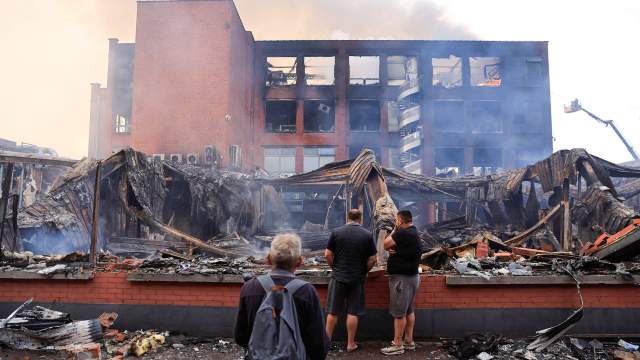 17 yaşındaki Nahel'in Nanterre'de Alma semtinde bir trafik durması sırasında bir Fransız polis memuru tarafından öldürülmesinin ardından protestocularla polis arasında gece çıkan çatışmalarda yanan Tessi grubuna ait bir binaya bakıyorlar. Roubaix, kuzey Fransa, 30 Haziran 2023.