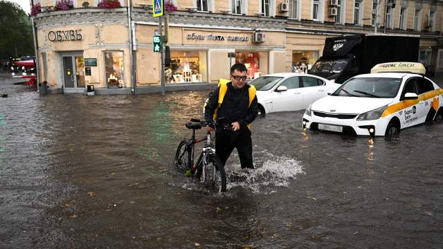 Мужчина с велосипедом на подтопленной улице в результате ливня в Москве