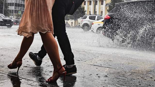 Люди идут по Садовому кольцу во время дождя в Москве