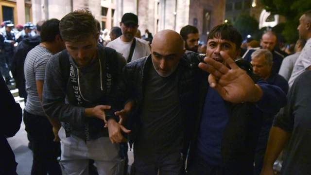 Мужчины помогают раненому в ходе протестов в связи с обострением ситуации в Нагорном Карабахе на площади Республики в Ереване