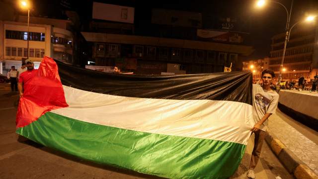 Иракцы держат палестинский флаг, принимая участие в акции протеста после того, как сотни палестинцев погибли в результате взрыва в больнице «Аль-Ахли» в секторе Газа