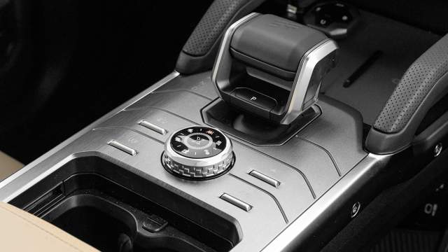 Рядом с массивным селектором трансмиссии — шайба для выбора режима движения и четыре физические кнопки, которые отвечают за внедорожный «круиз», систему кругового обзора, обогрев стекла и кондиционер