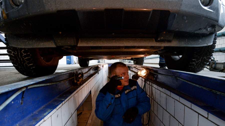 Сотрудник станции ТО проводит технический осмотр автомобиля