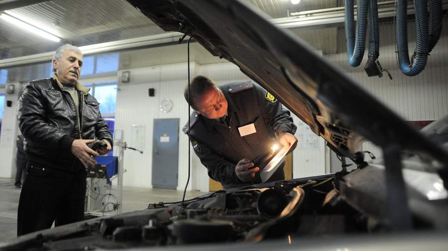 Сотрудник ГИБДД сверяет номера двигателей автомобиля во время технического осмотра