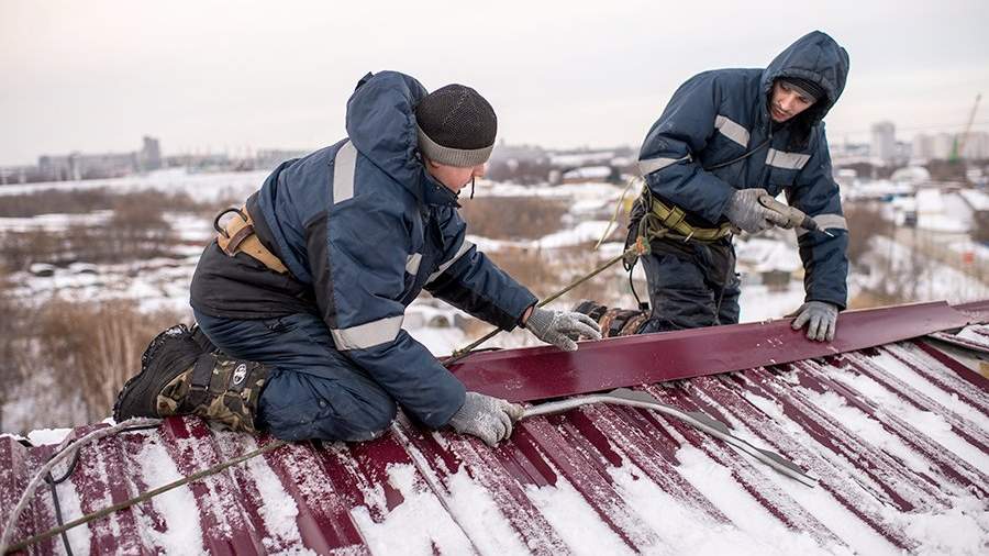 Рабочие ремонтируют крышу жилого дома 