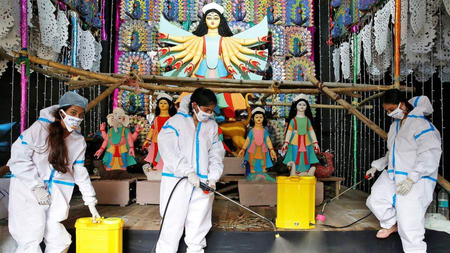 Женщины дезинфицируют платформу в преддверии фестиваля Дурга-пуджа