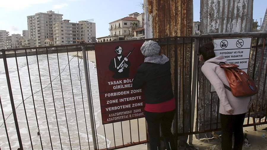 Women look through the fence at the closed part of Varosha