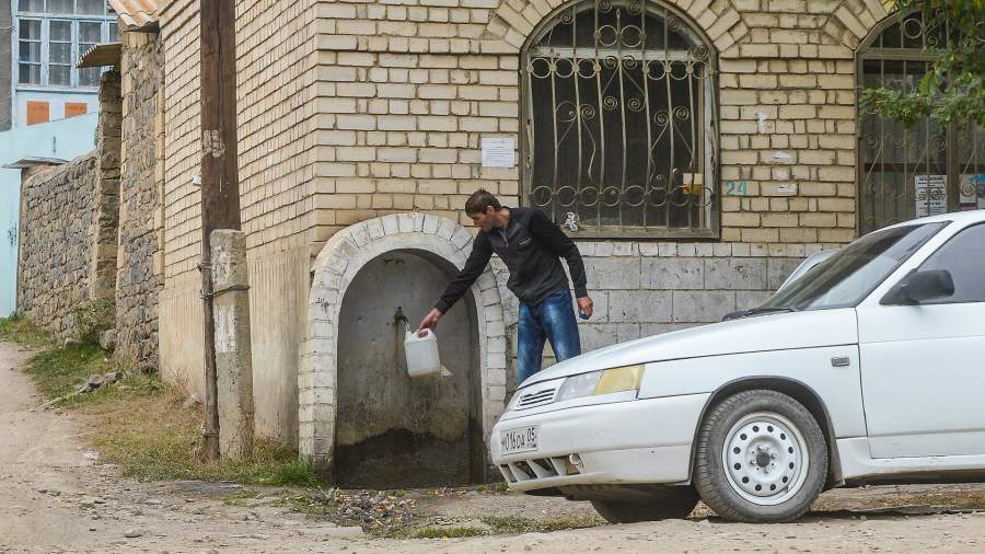 Мужчина набирает воду в канистру на улице дагестанского села