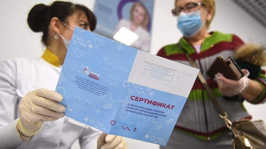Медицинский работник выдает сертификат о вакцинации от COVID-19 женщине