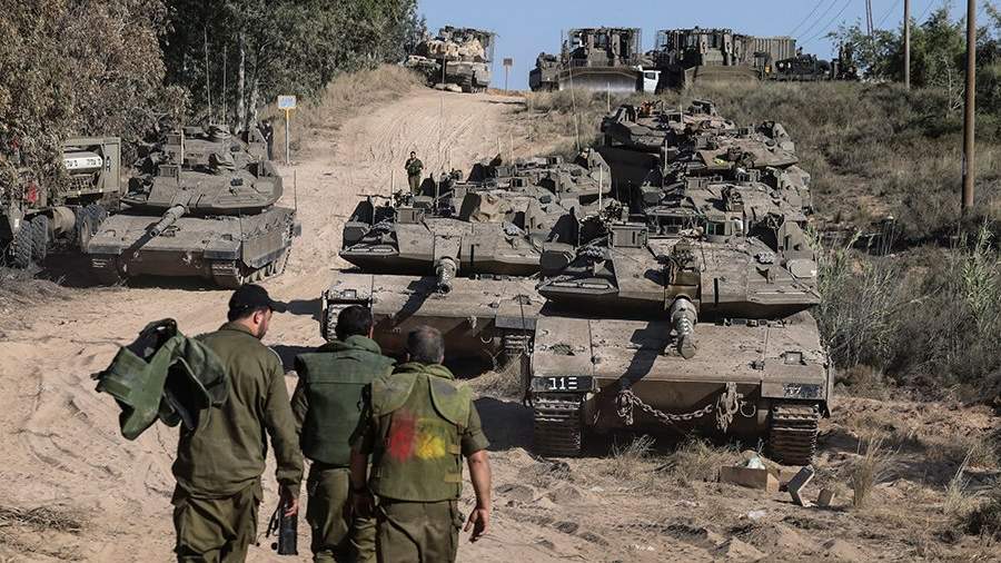 Израильские солдаты ходят вокруг танков в поле недалеко от границы между Израилем и сектором Газа