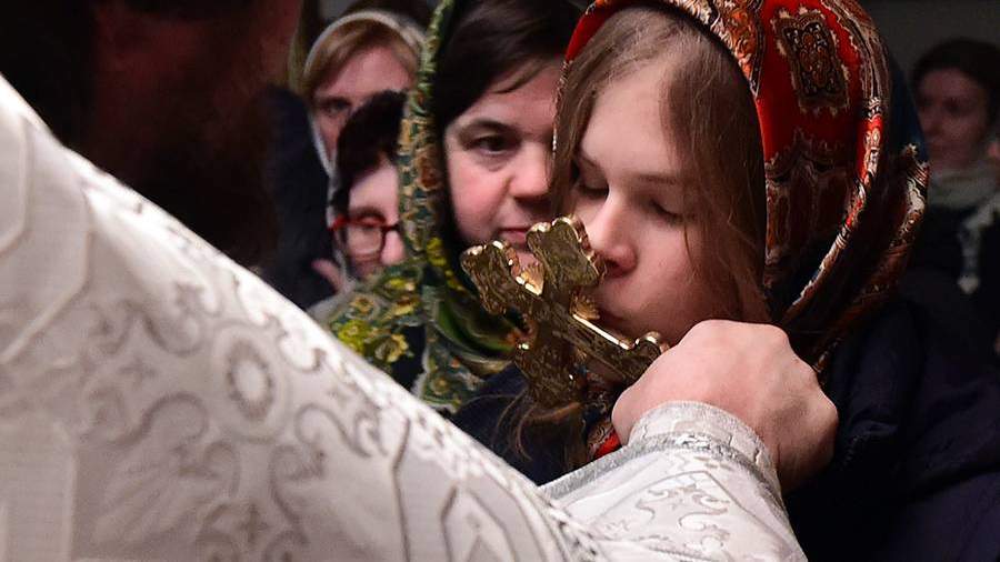 Девушка целует крест в церкви