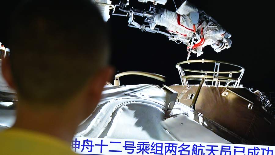 A man watches a live TV broadcast of two astronauts from the Chinese spacecraft Shenzhou 12 performing space operations outside the main module of the Chinese space station.