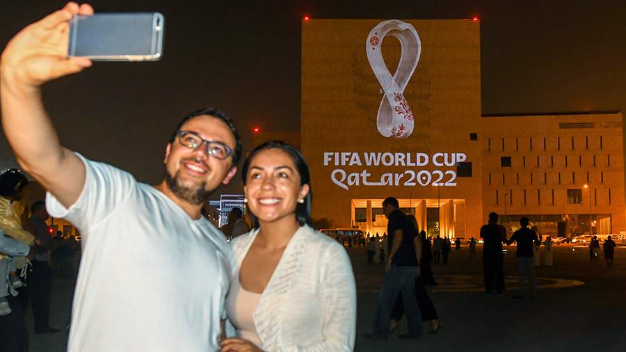 Люди фотографируются на фоне эмблемы Чемпионата мира по футболу