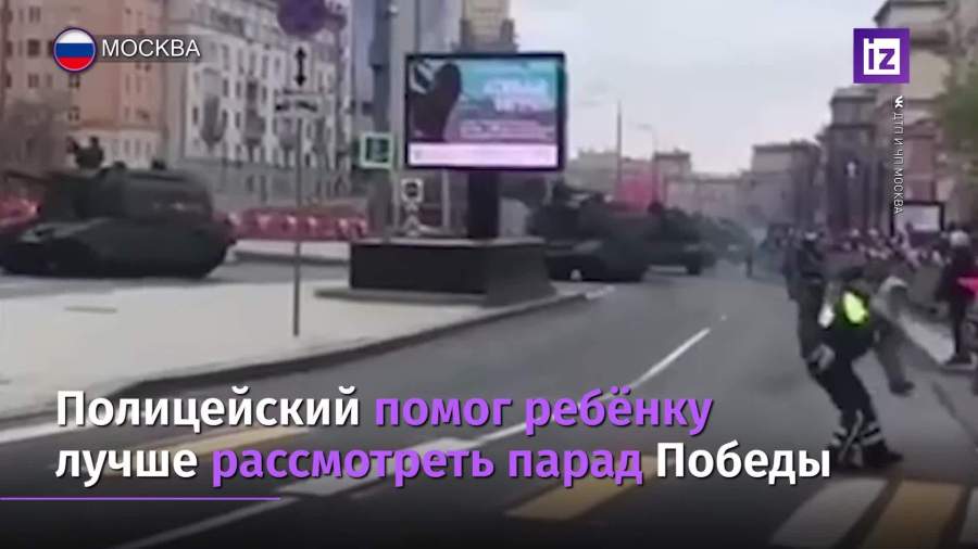 Полицейский взял на руки мальчика, чтобы тот посмотрел парад