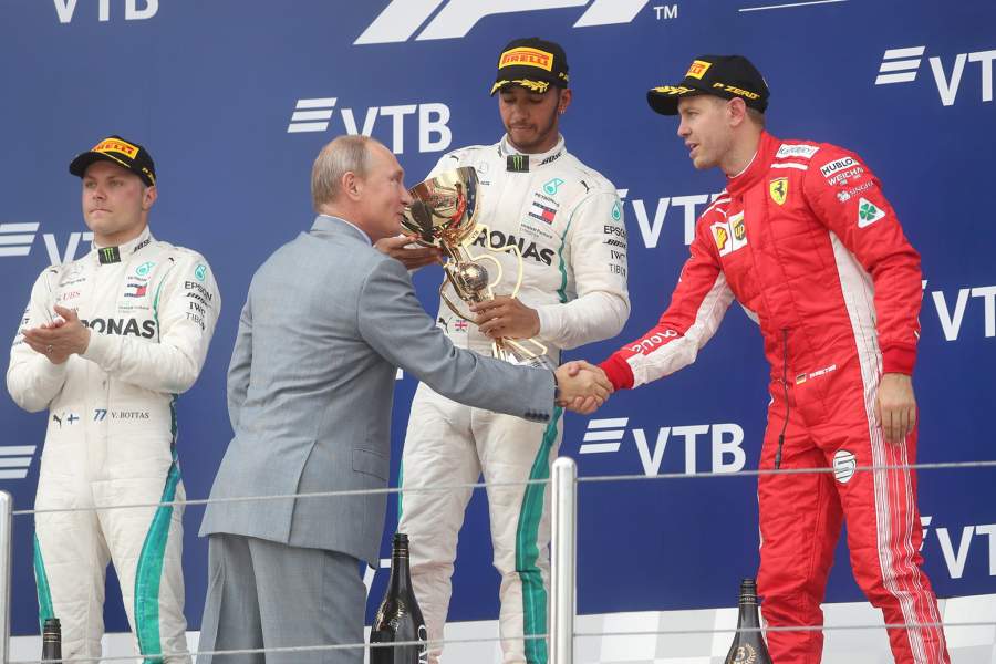 Президент РФ Владимир Путин на церемонии награждения призеров российского этапа чемпионата мира по кольцевым автогонкам в классе "Формула-1" на "Сочи Автодроме". Слева - гонщик команды «Мерседес» Валттери Боттас, в центре - гонщик команды «Мерседес» Льюис Хэмилтон, справа - гонщик команды «Феррари» Себастьян Феттель  