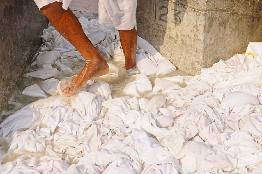 Мужчины-прачки замачивают белье с мыльными орехами, топчут его ногами