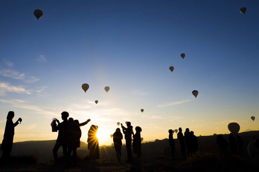 Туристы фотографируются на фоне воздушных шаров в Каппадокии