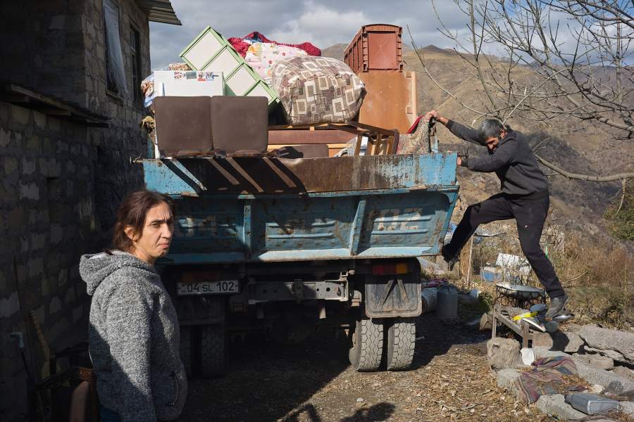 Женщина и мужчина у грузовой машины с вещами.