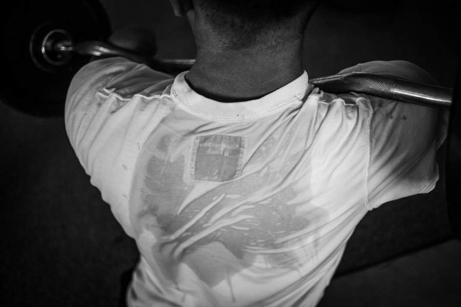 Алексей занимается со штангой во время тренировки в спортивном зале.