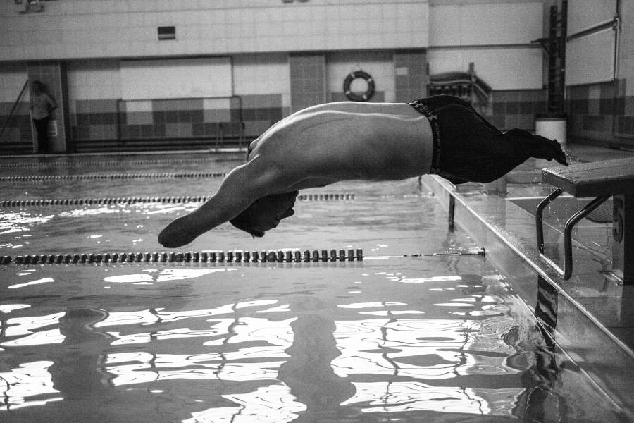 Алексей совершает прыжок в воду во время тренировки в бассейне.