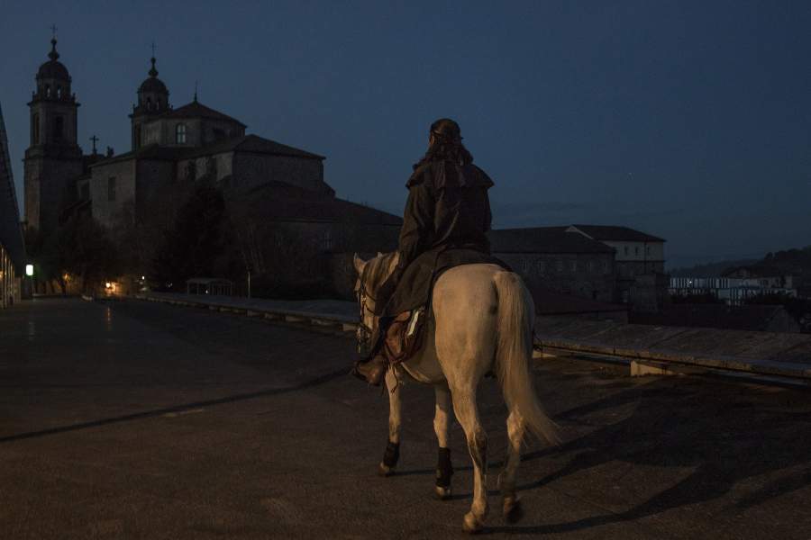 Мужчина на коне идет по дороге.