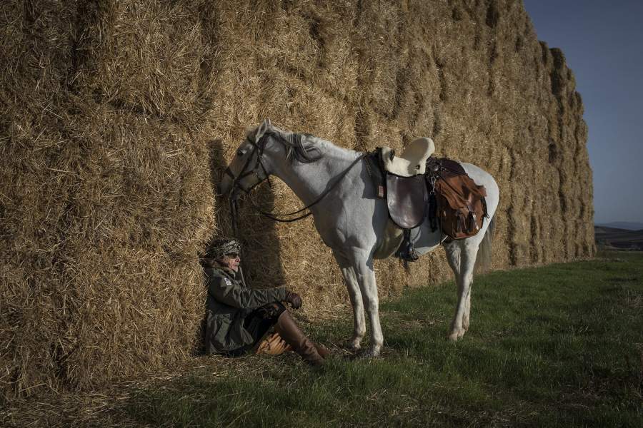 Мужчина присел отдохнуть у стогов сена.