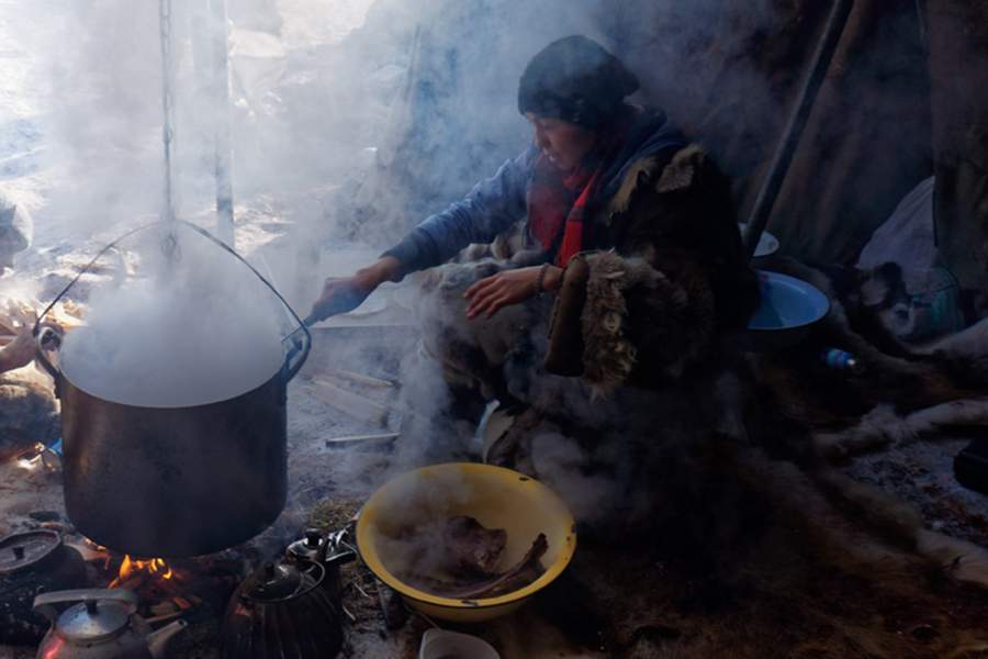 Женщина встречает у входа жилища с огнем для обряда очищения