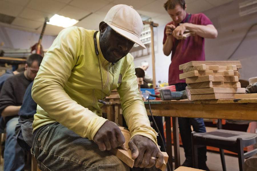 Подмастерья обрабатывают деревянные заготовки наждачной бумагой 
